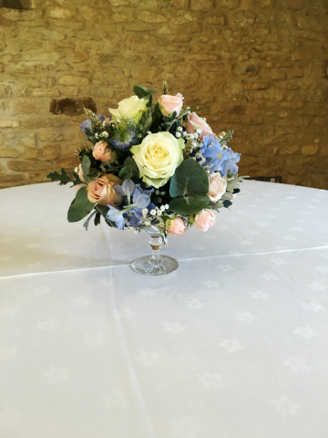Vintage cake stand domed display of light blue, Pink and White at Kingscote barn. Floral design by Cotswold Blooms, wedding florist based in Cheltenham.