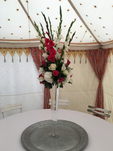 Tall Gladioli, Calla, Lily and Hydrangea table display in bright pink and white in a yurt. Floral design by Cotswold Blooms, wedding florist based in Cheltenham.