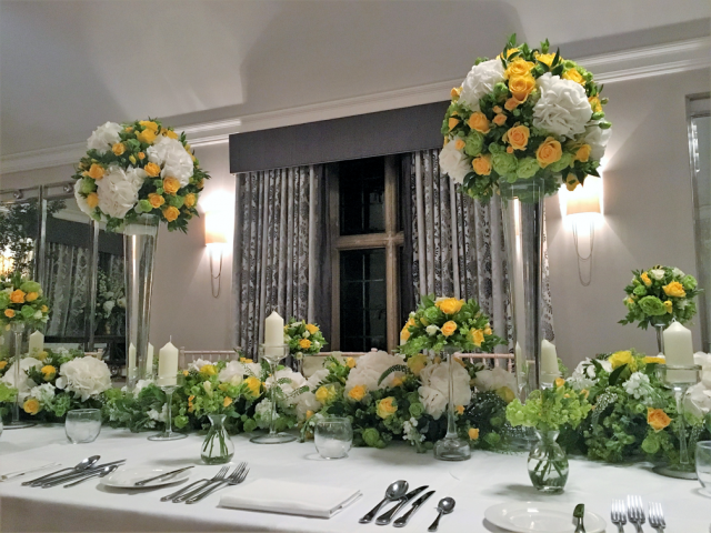 Yellow and white table display at Foxhill Manor, including Roses, Hydrangea and pops of lime green Guelder Rose. Floral design by Cotswold Blooms, wedding florist based in Cheltenham.