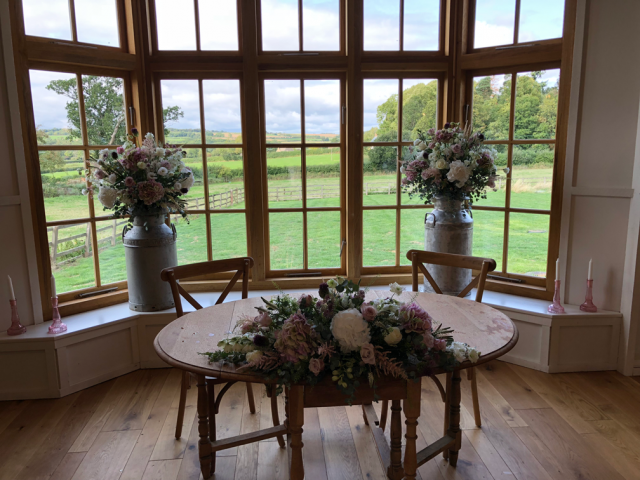Milk churns and a long and low display at the Grange, Hyde House. Floral design by Cotswold Blooms, wedding florist based in Cheltenham.