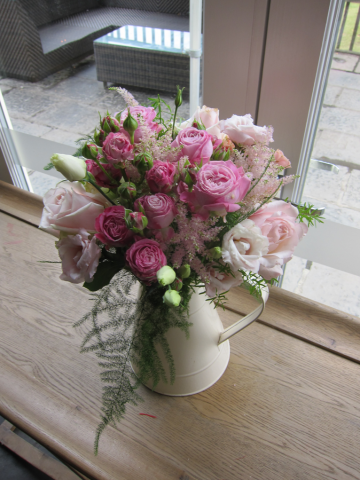 Mixed Roses in pink tones in and a cream enamel jug. Floral design by Cotswold Blooms, wedding florist based in Cheltenham.