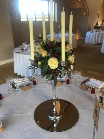 Winter wedding candelabra display with berries and pine. Floral design by Cotswold Blooms, wedding florist based in Cheltenham.