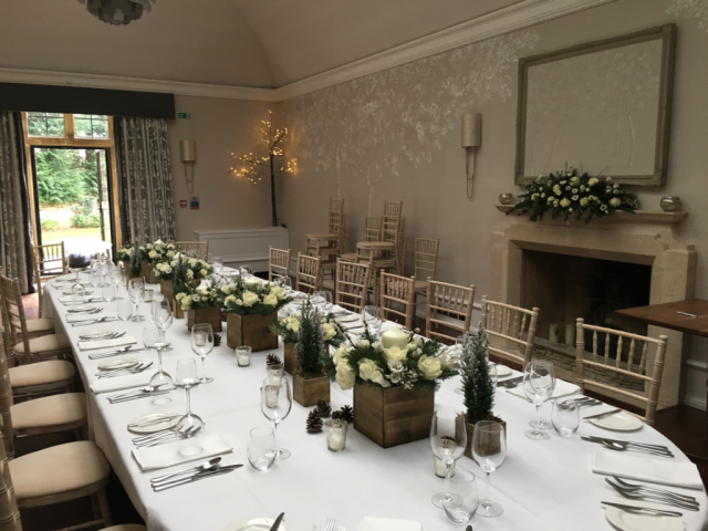 Foxhill manor set up for a winter dinner with trees, roses, and a snowy feel. Floral design by Cotswold Blooms, wedding florist based in Cheltenham.
