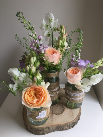Juliet Roses, Lilac Stocks and Sweet Pea table displays on a wood slice. Floral design by Cotswold Blooms, wedding florist based in Cheltenham.