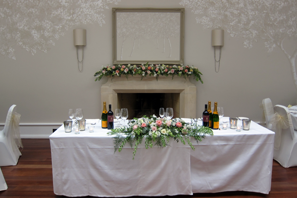 Top table and mantelpiece display at Foxhill Manor. Floral design by Cotswold Blooms, wedding florist based in Cheltenham.