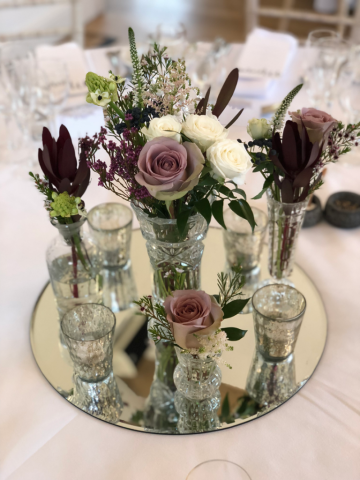 Cut glass display on a mirror base with silver tea lights filled with Amnesia Roses, Safari and Veronica. Floral design by Cotswold Blooms, wedding florist based in Cheltenham.