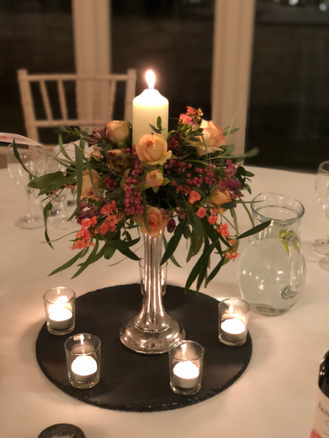 Slate plate with silver stand display with mixed textures and a candle.  Floral design by Cotswold Blooms, wedding florist based in Cheltenham.