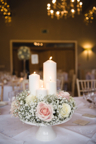 Gypsophila and Roses on a cake stand with mixed candles in light pink and white. Floral design by Cotswold Blooms, wedding florist based in Cheltenham.