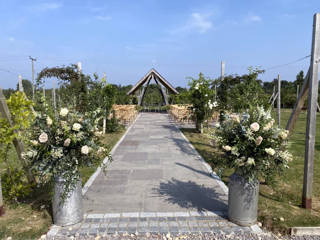 Outdoor wedding styling with rustic milk churn flower arrangements at Cider Mill Barn