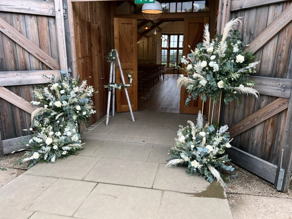 Natural green and white floral installation at ceremony room entrance with dried and fresh flowers