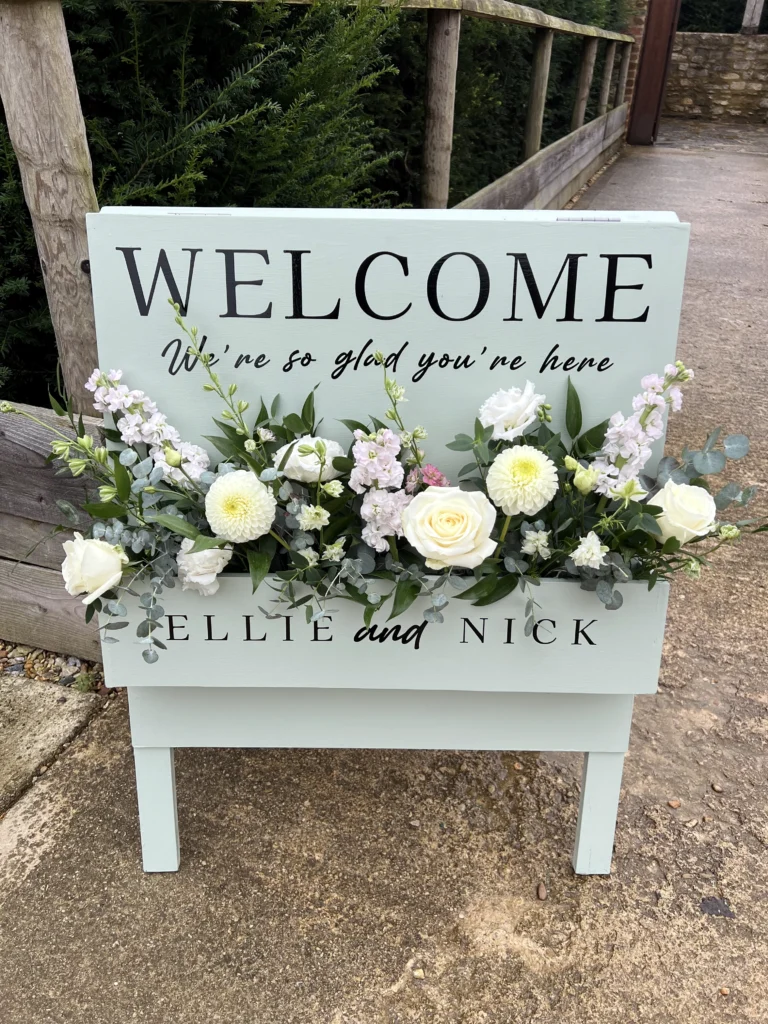 Welcome entrance wedding sign with rose and foliage arrangement