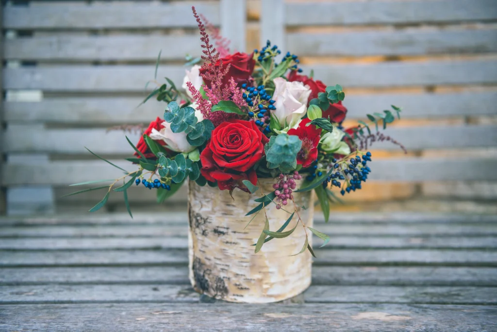 Seasonal winter birch bowl arrangement with roses and blue viburnum berries