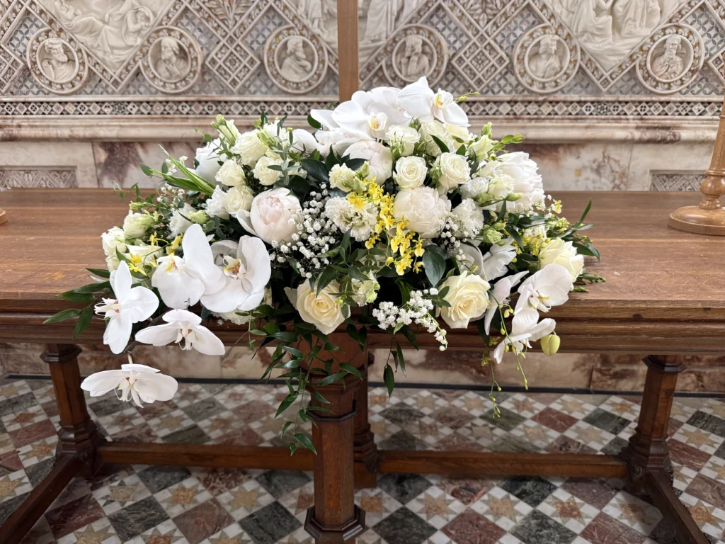 Elegant asymmetrical top table display of orchids, peonies and roses at Sudeley Castle