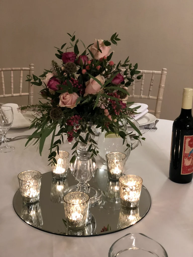 Wedding table centrepiece in plum and light pink on glass stand with tealights