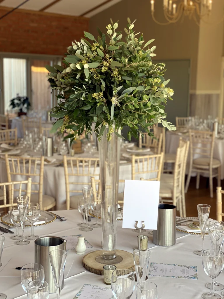 Glass lily vase arrangement with rustic mixed foliage