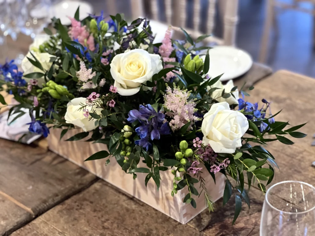 Floral arrangement in a rustic box with white, pink and blue flowers