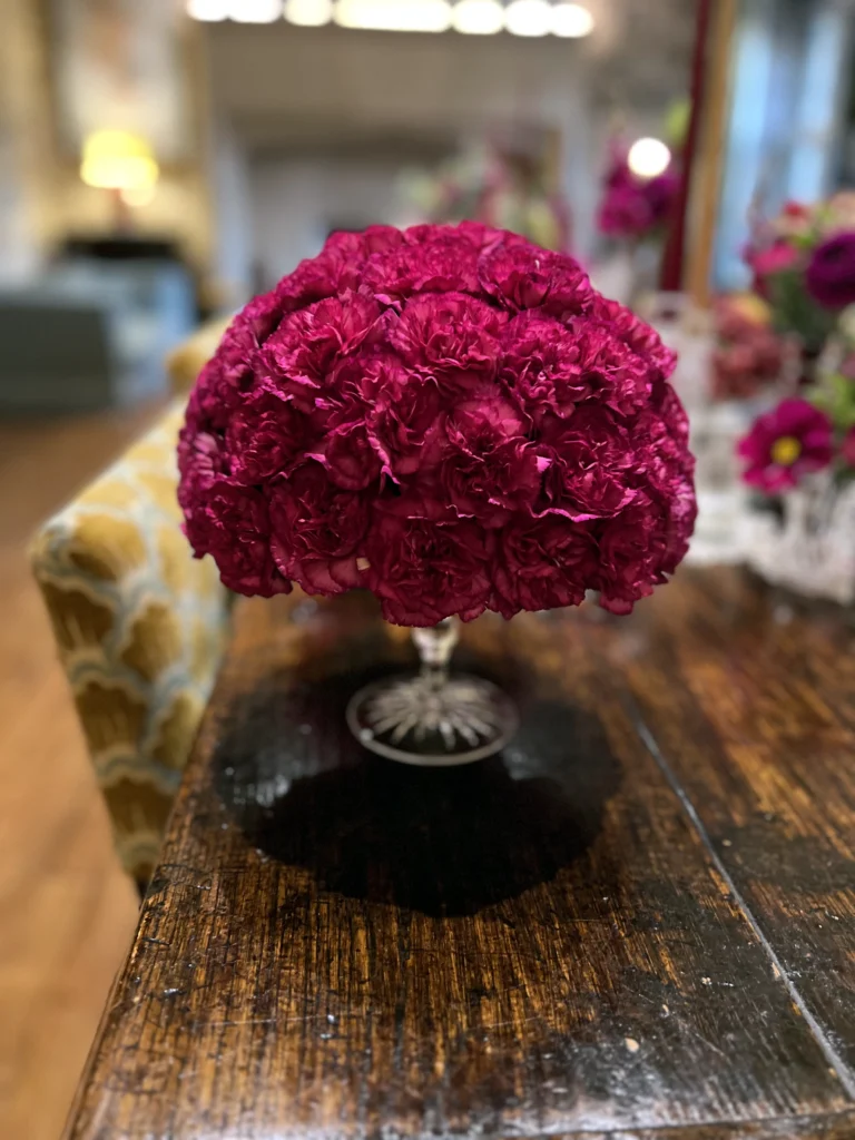 Vintage-style carnation display elevated on a cut glass stand