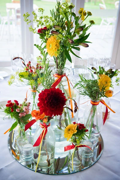 Wedding table display in mixed bottles with vibrant flowers