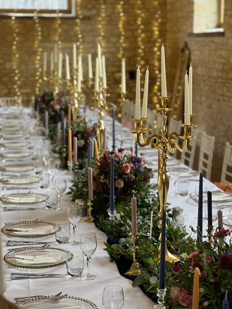 Intimate wedding table display with candles, natural foliage and gold candelabras
