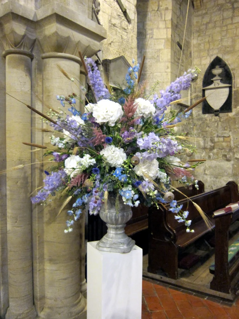 Hydrangea and delphinium pedestal arrangement with dried boho florals in church setting