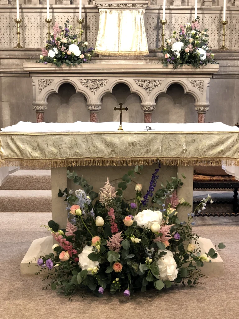 Meadow-style floral displays dressing the church altar for a wedding ceremony