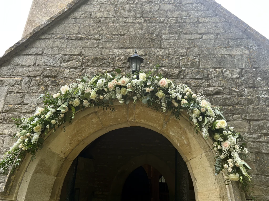 Church entrance arch with eucalyptus, roses, delphinium and gypsophila