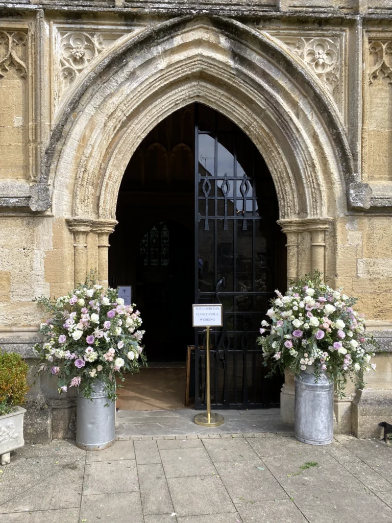 Country garden milk churn floral arrangement at church entrance