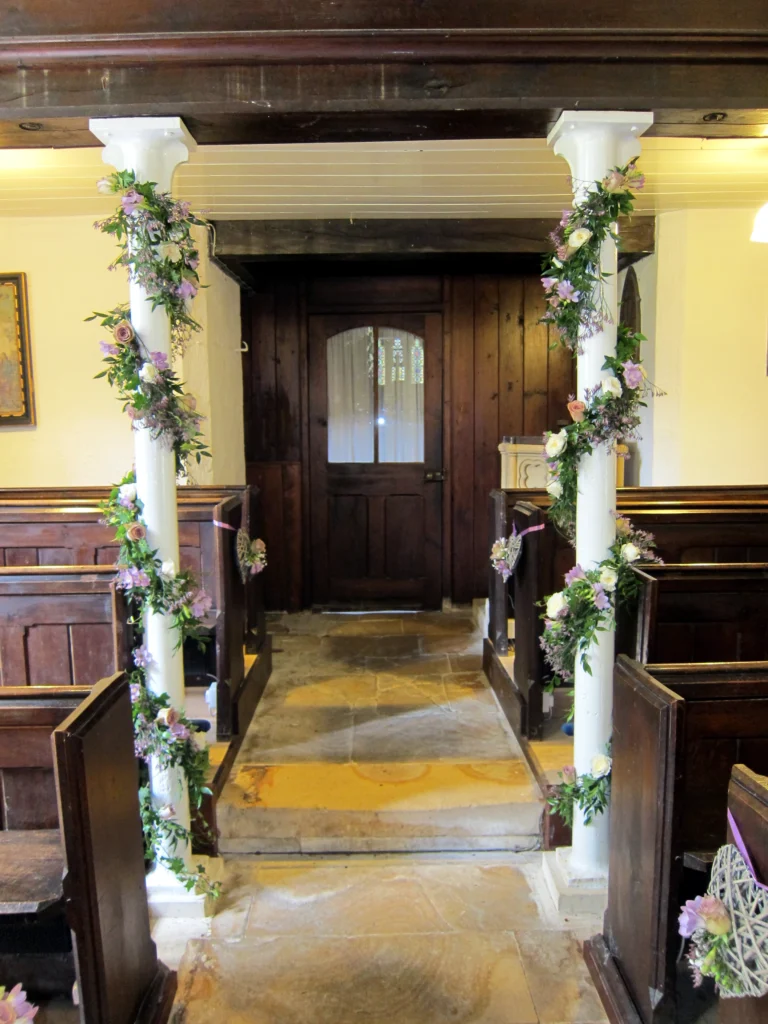 Church pillar flowers with roses, freesia and flowing greenery garlands