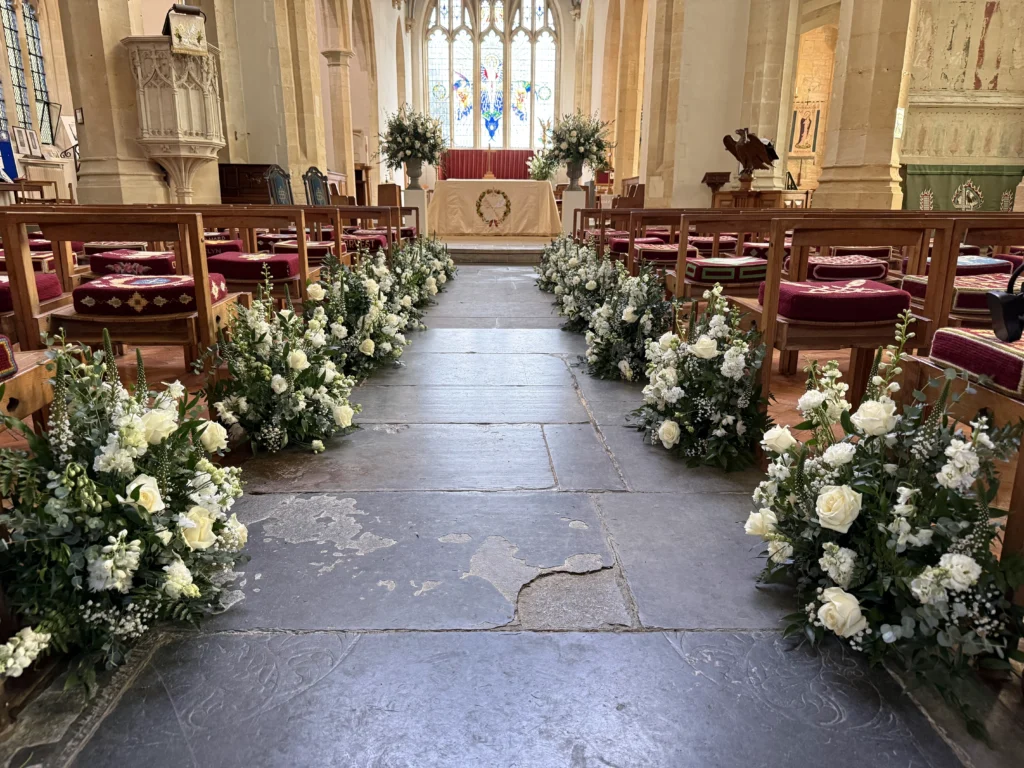 Elegant white and green pedestal and meadow floral displays in church