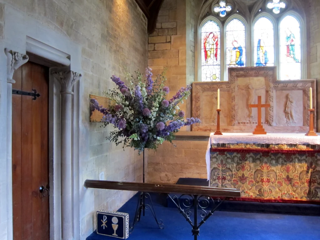 Purple delphinium and allium pedestal flower displays in church