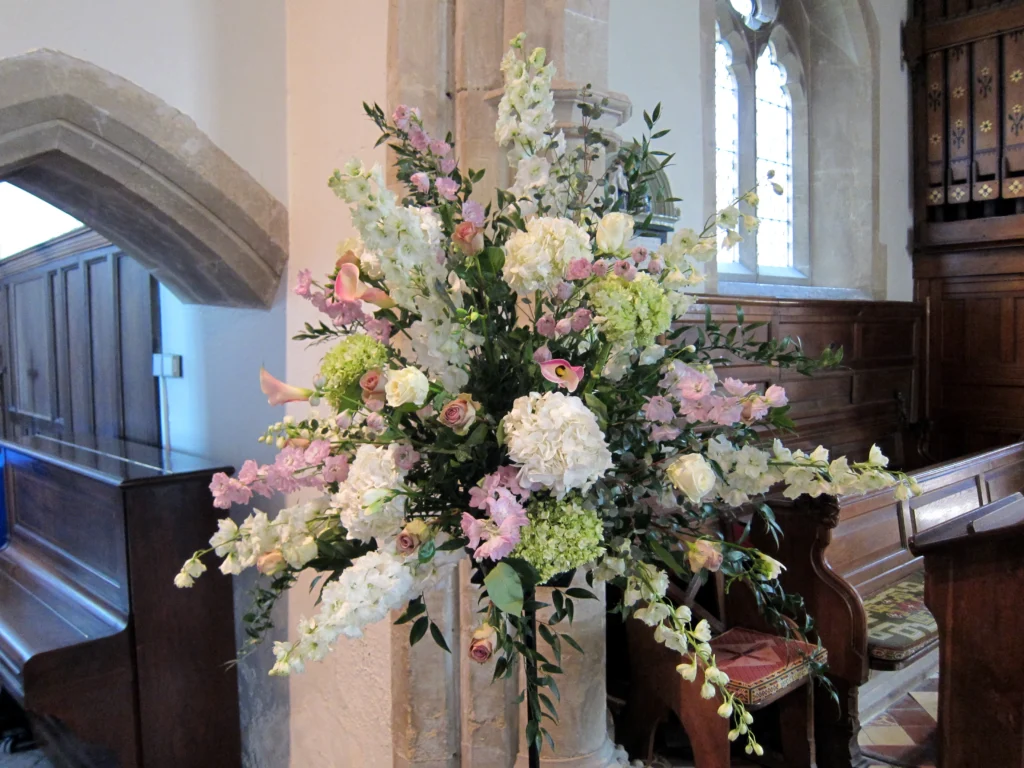 Traditional white and pink pedestal arrangement with hydrangea, roses and delphinium