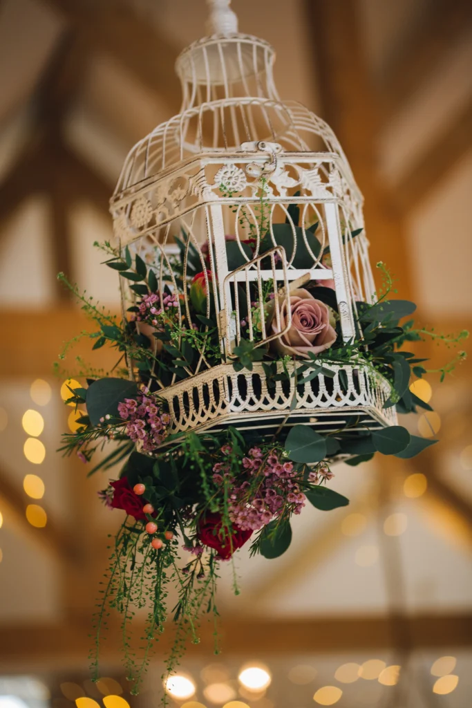 Floral birdcage hanging display with roses and greenery