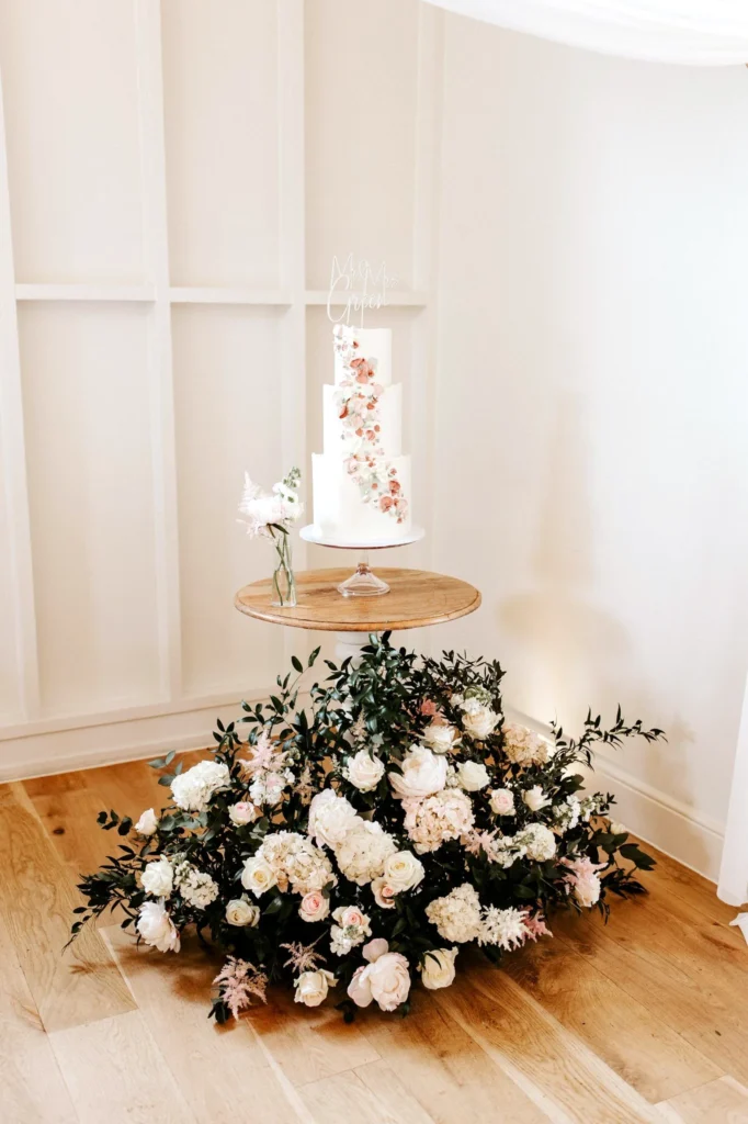 Floral meadow arrangement at cake table base with hydrangeas, roses and peonies