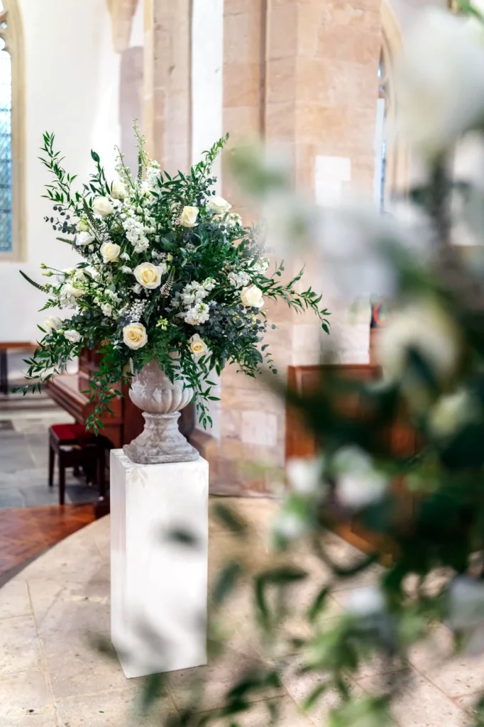 Church floral display featuring roses and eucalyptus in a stone urn at Northleach Church
