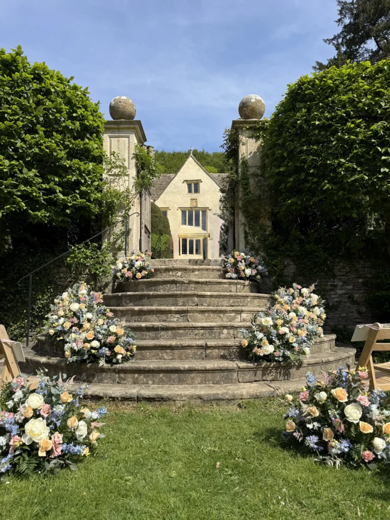 Delicate pastel floral staircase arrangement at Owlpen Manor