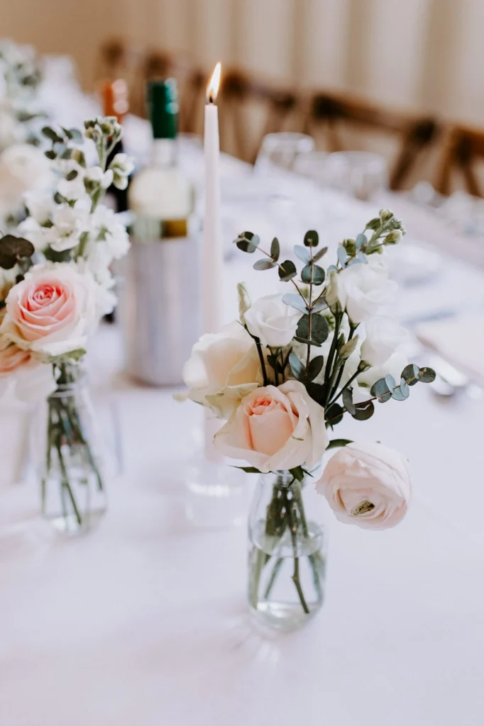 Elegant rose and ranunculus bud vases running along the top table