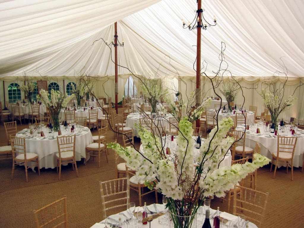 Tall delphinium pedestal displays inside a private marquee wedding in the Cotswolds