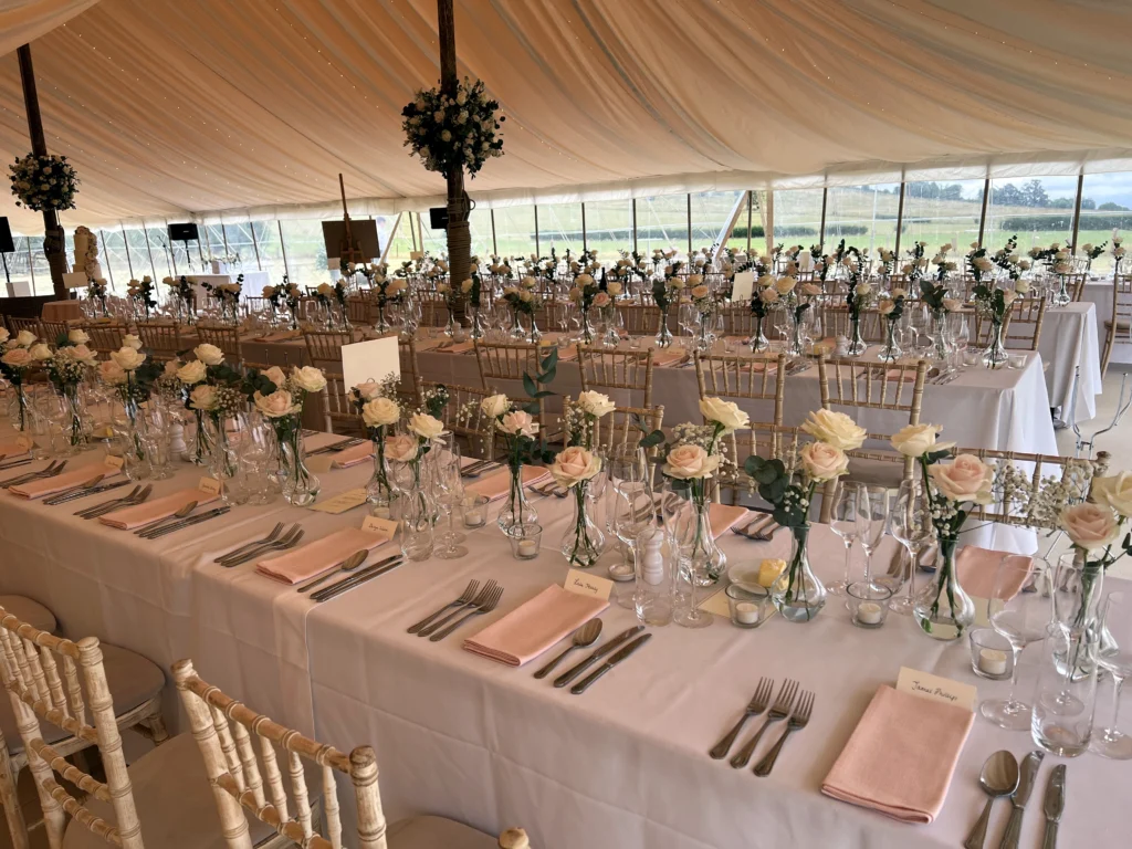 Rose bud vases and floral balls dressing the tables of a Cotswold marquee wedding