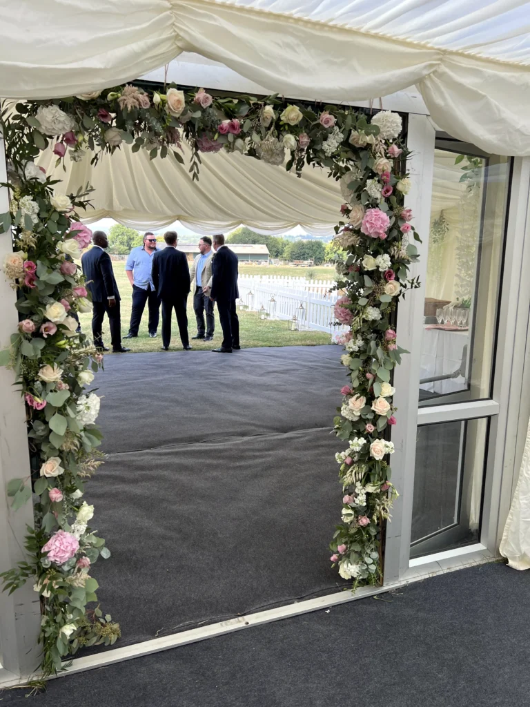 Floral entrance arch with roses, peonies and eucalyptus for a Cotswold marquee wedding
