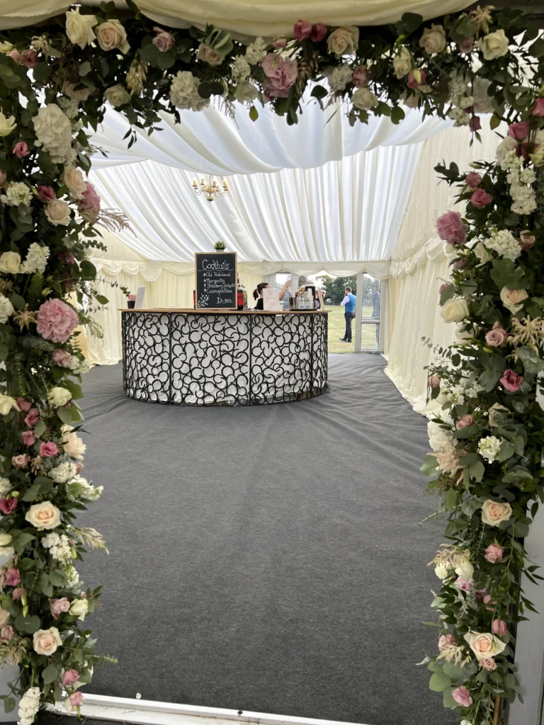 Rose, peony and eucalyptus flower arch framing the entrance to a Cotswold marquee wedding