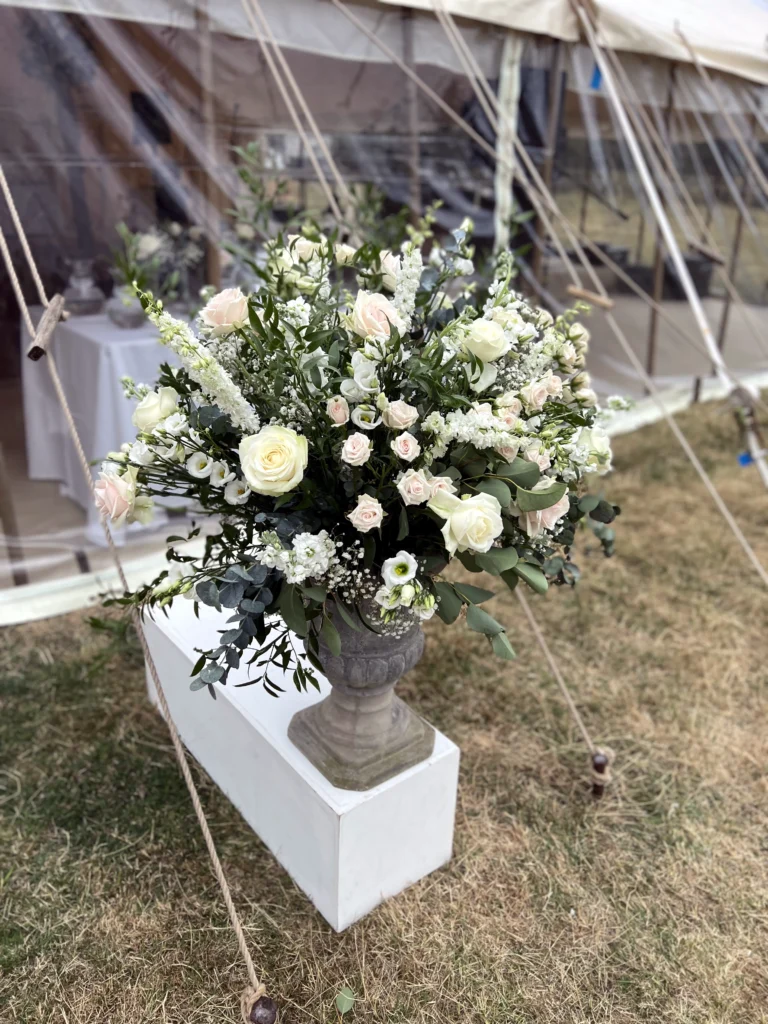 Traditional urn display with blue and white roses, hydrangea and foliage at a marquee entrance
