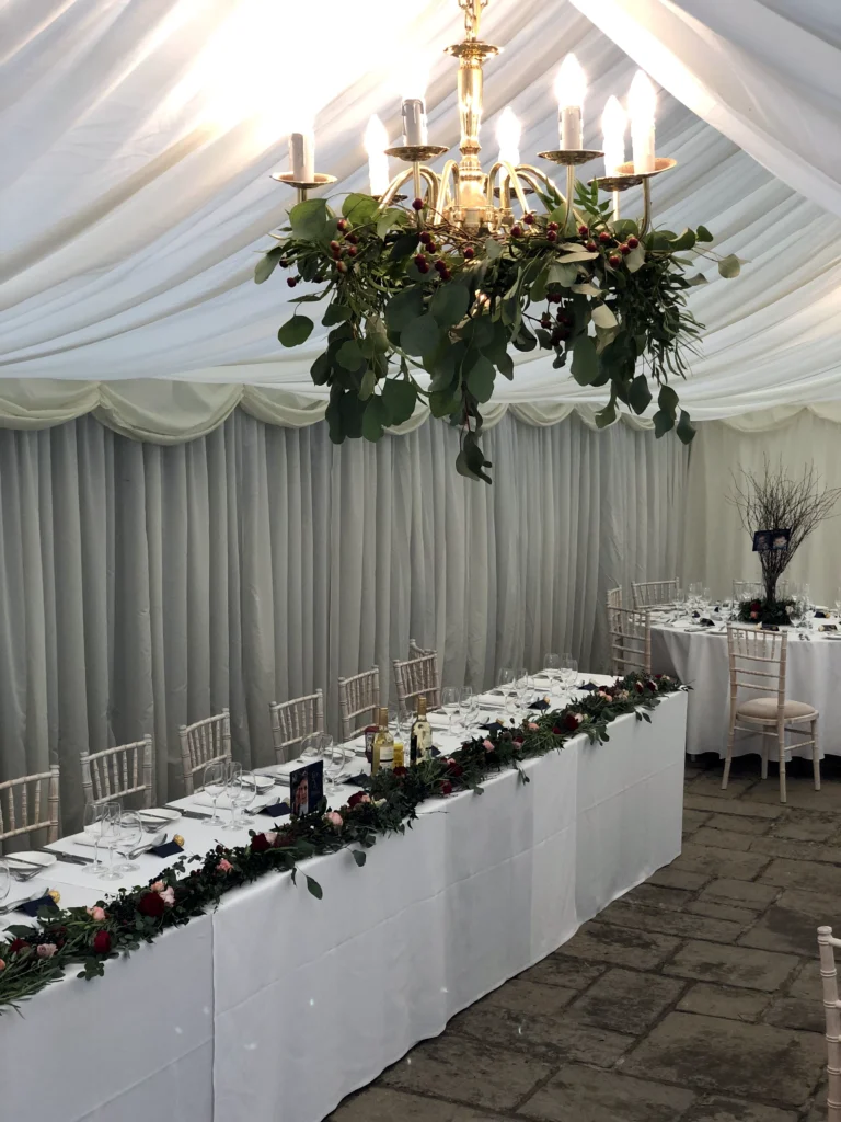 Foliage and twig floral displays inside a rustic Cotswold marquee wedding