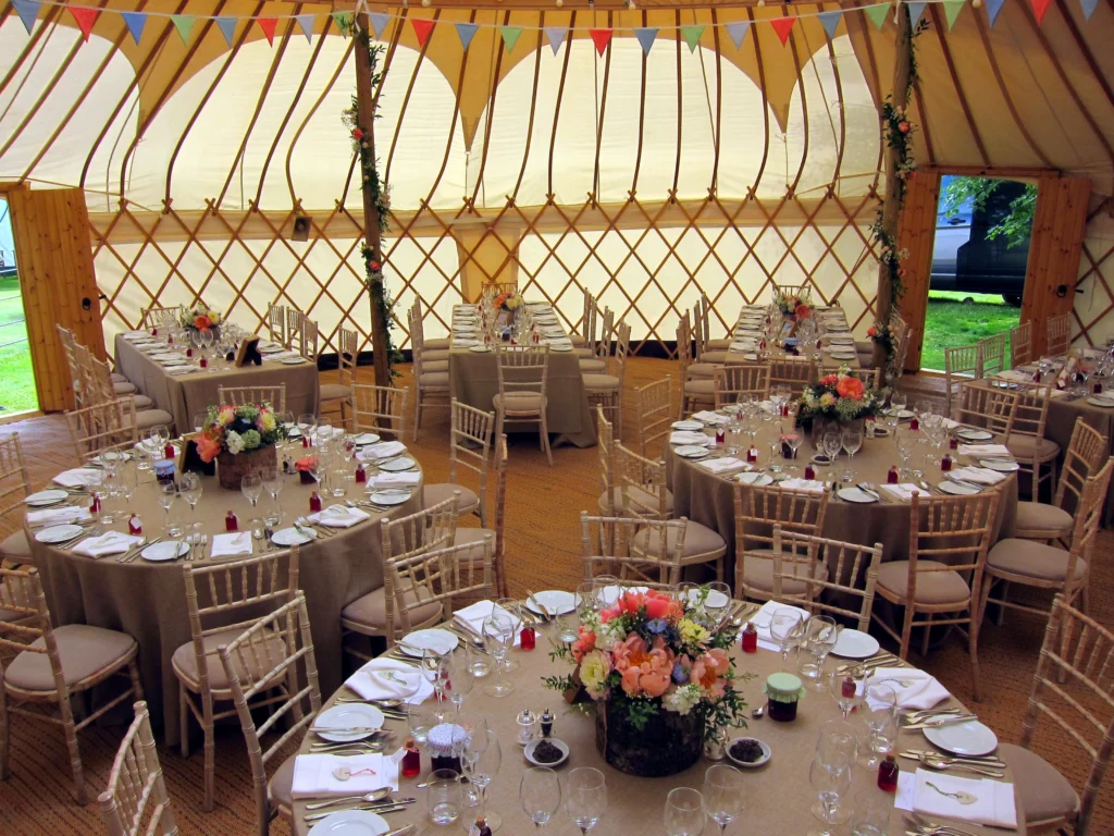 Wedding flowers inside a yurt with floral pole decorations and elegant table centrepieces for a Cotswolds wedding