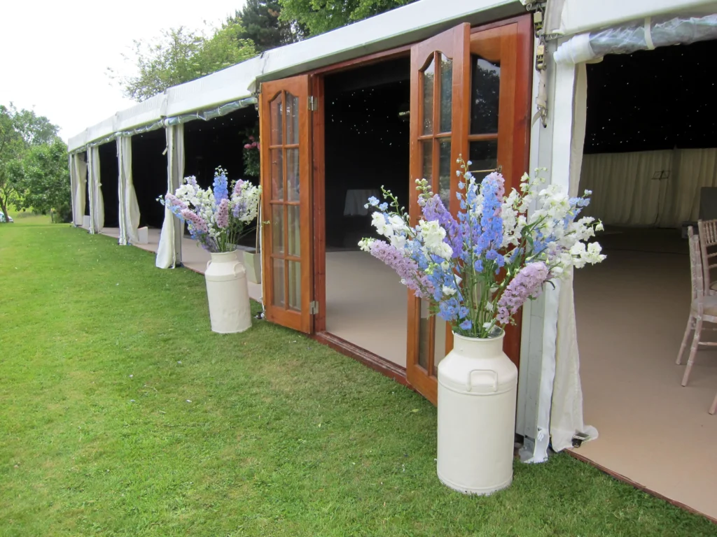 Tall delphinium flower displays framing the entrance to a wedding marquee in the Cotswolds