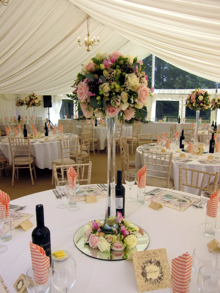 Elegant lily vase display with rose-filled base creating a romantic country garden wedding centrepiece