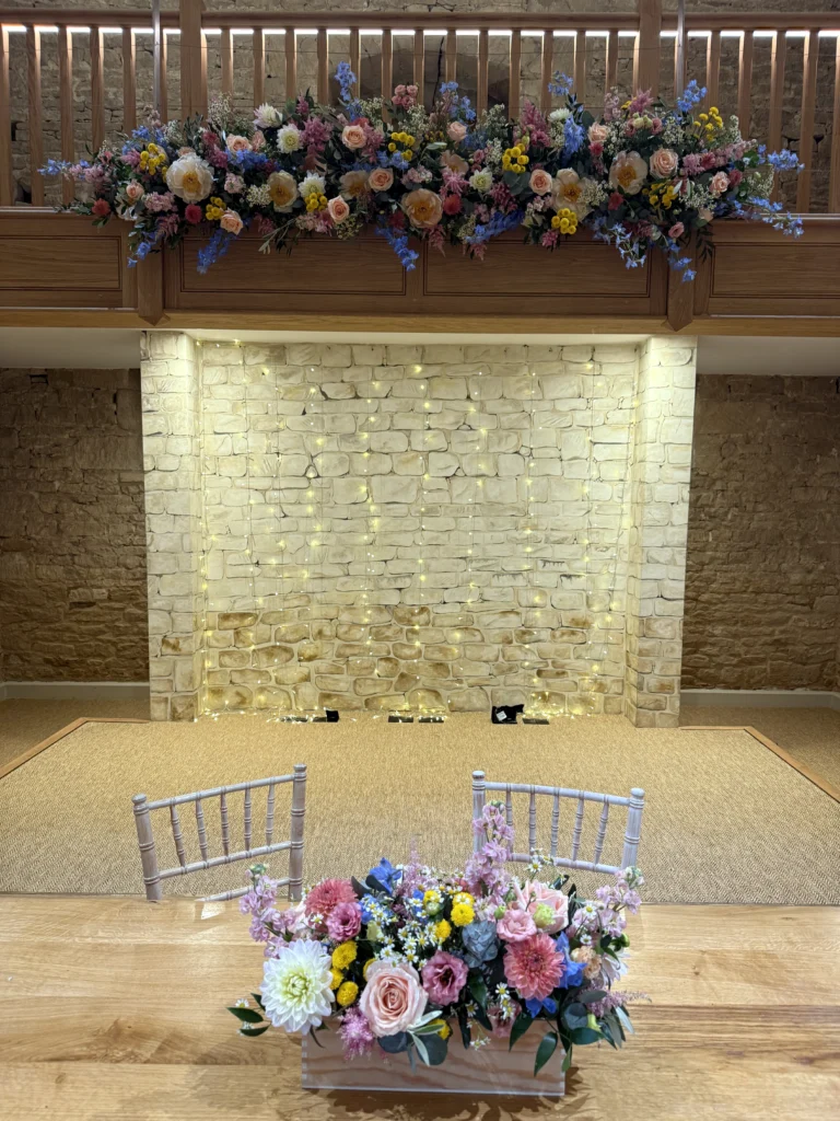 Bright floral installation Great Tythe Barn wedding Cotswold Blooms